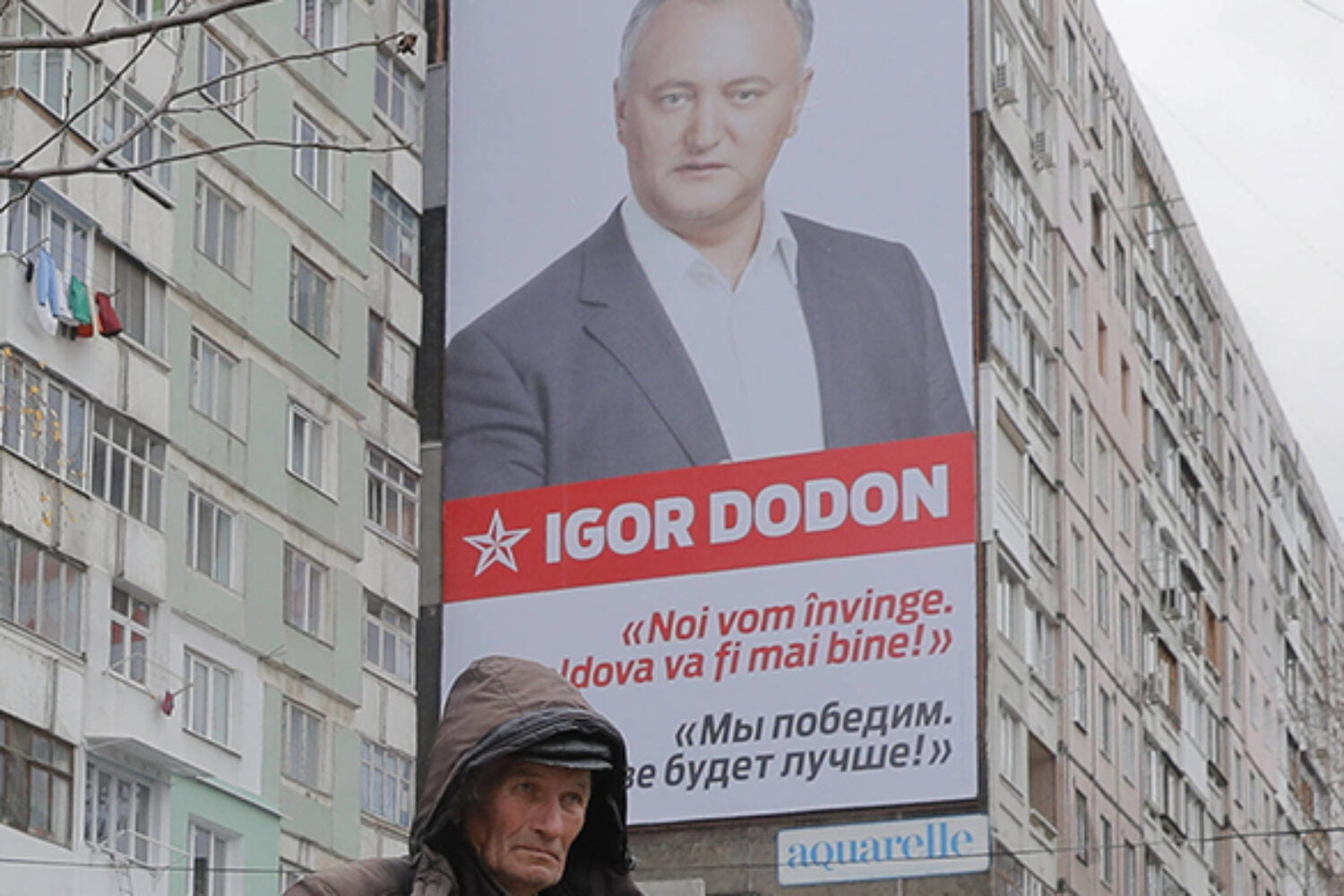 A flower vendor stands back dropped by a large poster of socialist presidential candidate Igor Dodon, placed on an apartment block, which reads in Russian and Romanian "We will win and it will be better in Moldova" in Chisinau, Moldova, Saturday, Nov. 12, 2016. Moldovans will directly elect their president on Sunday for the first time in 20 years the favorite is Socialist Igor Dodon, who wants the ex-Soviet republic to return to the Russian orbit, while rival Maia Sandu believes the agricultural nation of 3.5 million, bordering Ukraine and European Union member Romania, would secure a more prosperous future in Europe. (AP Photo/Vadim Ghirda)