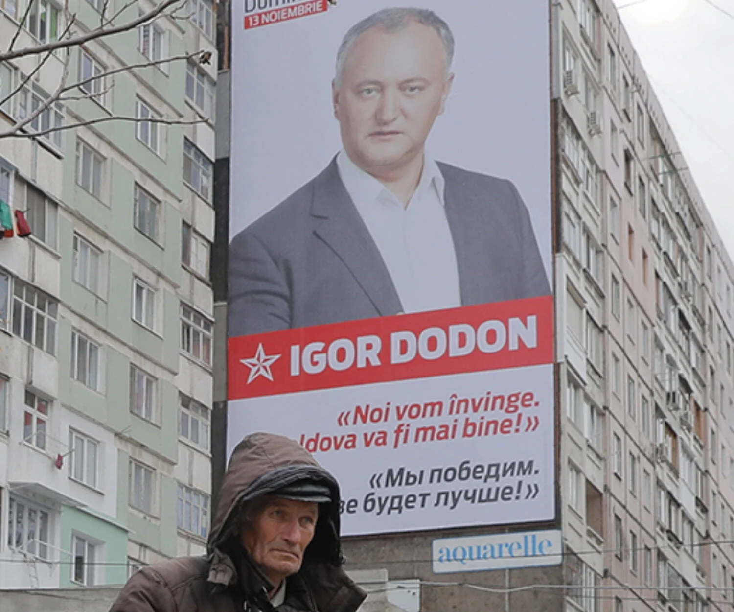 A flower vendor stands back dropped by a large poster of socialist presidential candidate Igor Dodon, placed on an apartment block, which reads in Russian and Romanian "We will win and it will be better in Moldova" in Chisinau, Moldova, Saturday, Nov. 12, 2016. Moldovans will directly elect their president on Sunday for the first time in 20 years the favorite is Socialist Igor Dodon, who wants the ex-Soviet republic to return to the Russian orbit, while rival Maia Sandu believes the agricultural nation of 3.5 million, bordering Ukraine and European Union member Romania, would secure a more prosperous future in Europe. (AP Photo/Vadim Ghirda)