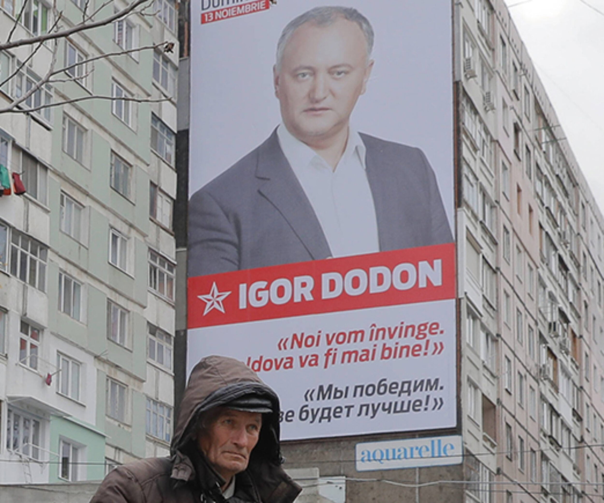 A flower vendor stands back dropped by a large poster of socialist presidential candidate Igor Dodon, placed on an apartment block, which reads in Russian and Romanian "We will win and it will be better in Moldova" in Chisinau, Moldova, Saturday, Nov. 12, 2016. Moldovans will directly elect their president on Sunday for the first time in 20 years the favorite is Socialist Igor Dodon, who wants the ex-Soviet republic to return to the Russian orbit, while rival Maia Sandu believes the agricultural nation of 3.5 million, bordering Ukraine and European Union member Romania, would secure a more prosperous future in Europe. (AP Photo/Vadim Ghirda)