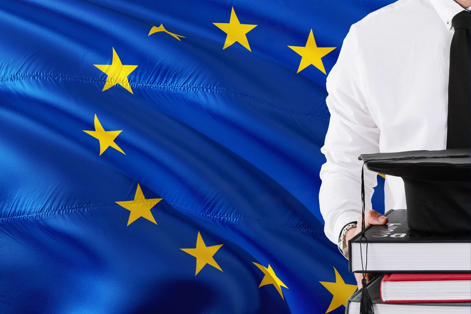 Successful European student education concept. Holding books and graduation cap over European Union flag background.